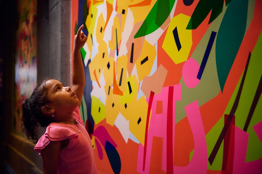 A child points up in wonder at a colourful vignette.