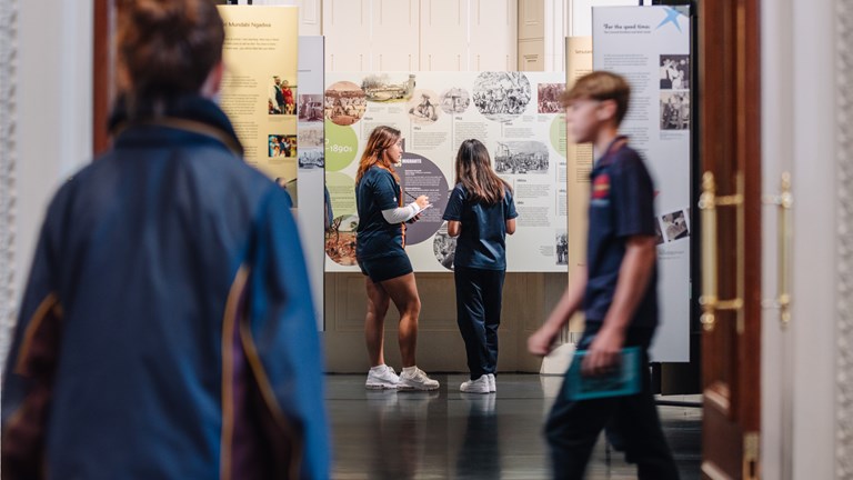 Four students with workbooks looking in a gallery.