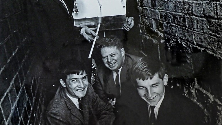 A group of young men in an alleyway holding a satellite.