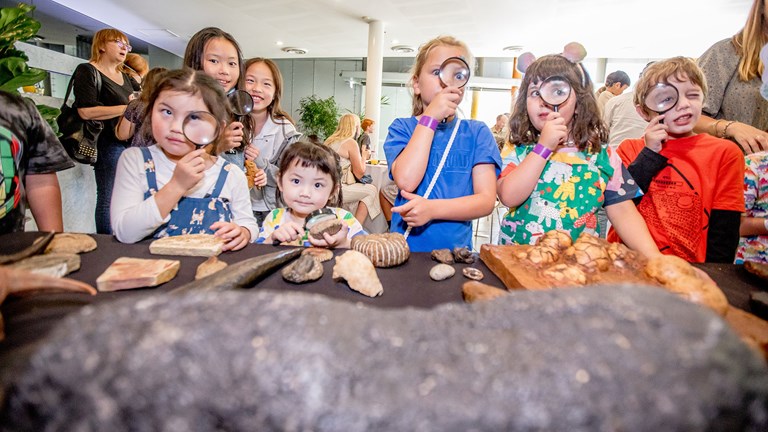 Children use magnifying glasses to examine dinosaur bones as part of Dinos Traces of the Past